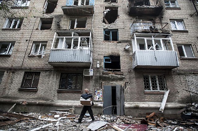 A man on Thursday carries his belongings from an apartment building damaged by shelling in eastern Ukraine’s Slovyansk.