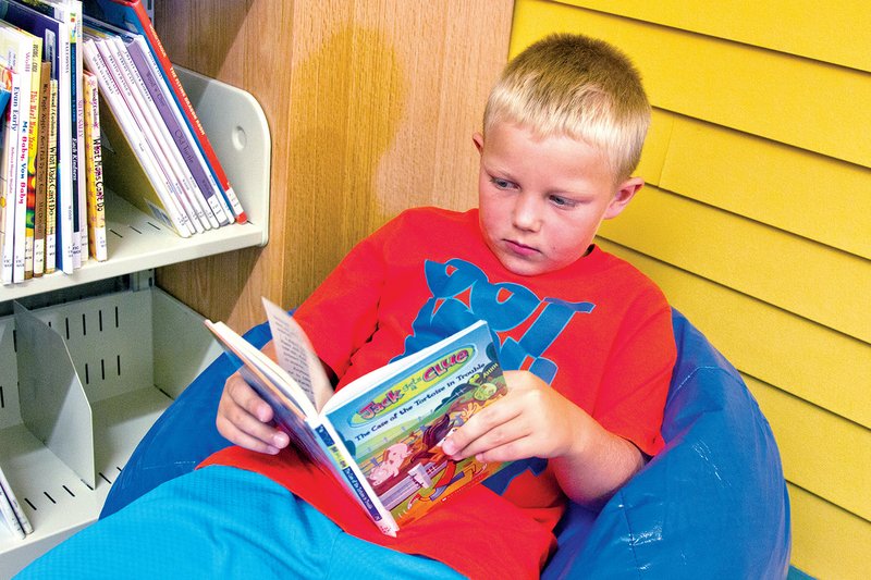 Colby Boyd, 7, relaxes on a bean bag while reading in the new Mary I. Wold Cleburne County Library in Heber Springs. The facility opened June 4 and has already seen checkouts triple.
