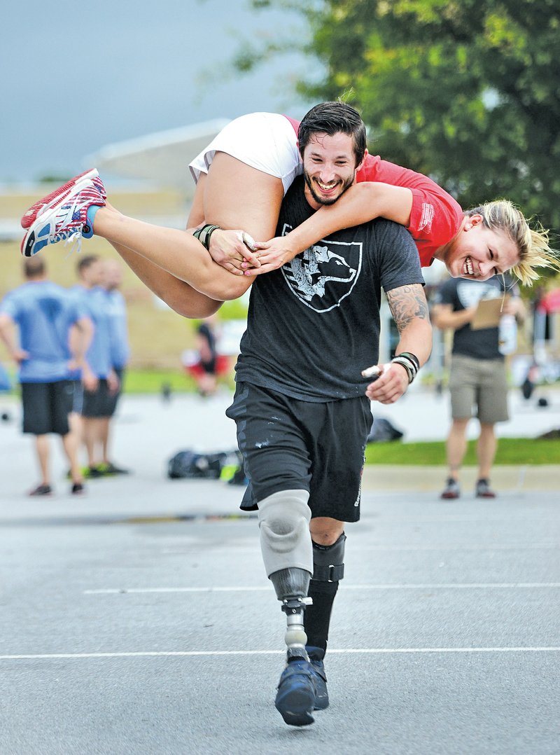  STAFF PHOTO SAMANTHA BAKER &#8226; @NWASAMANTHA Nicholas Perales, retired Marine Cpl., who sustain numerous injuries during his time in Afghanistan including a right leg amputation &#8220;buddy carries&#8221; workout partner Jessica Mesko on June 7, 2014 at Arvest Ballpark in Springdale during the 2014 Heroes WOD.