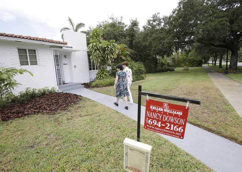 In this Thursday, May 29, 2014 photo, real estate broker Nancy Dowson, center right, with Keller Williams Realty, shows a house to prospective buyer Mary Tuttle, center, in Miami Shores, Fla. Freddie Mac releases weekly mortgage rates on Thursday, June 12, 2014.