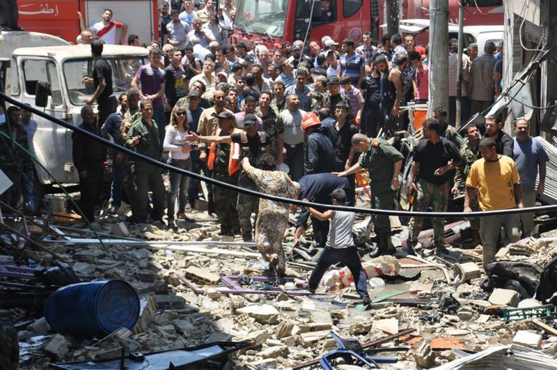 In this photo released by the Syrian official news agency SANA, Syrian citizens gather at a scene where a car bomb exploded in a pro-government neighborhood in central Homs, Syria, Thursday, June 12, 2014. Thursday's blast occurred in the Wadi Dahab district and killed several people, the Britain-based Syrian Observatory for Human Rights said. The activist group said five of the dead were civilians, but it was not clear whether the other two were civilians or pro-government gunmen. 