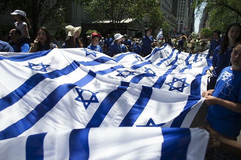 In this Sunday, June 1, 2014 file photo, revelers carry a banner made of Israeli flags as they march up Fifth Avenue during the Celebrate Israel Parade. Once a unifying cause for generations of American Jews, Israel is now bitterly dividing Jewish communities.