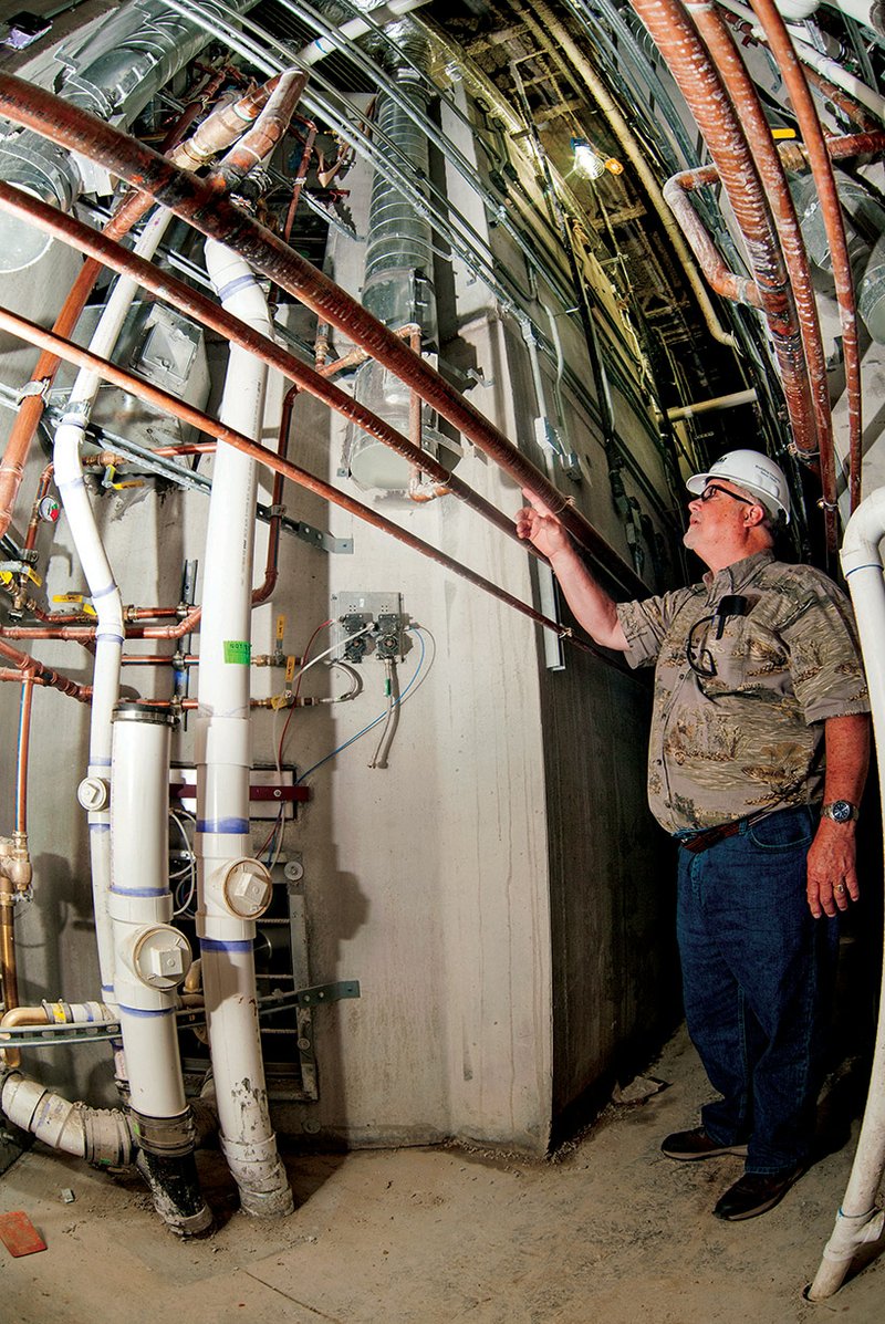 Jerry Pogue looks over the massive pipes and conduits that will supply water and electricity to the jail, as well as the security systems in a corridor that runs between the walls of each day room.