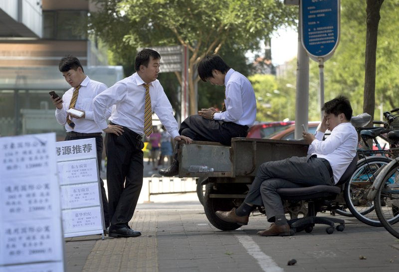 Real estate agents wait for potential buyers in Beijing earlier this month. Housing prices in China had
risen for 15 years before a recent slump that threatens the economy, analysts say.