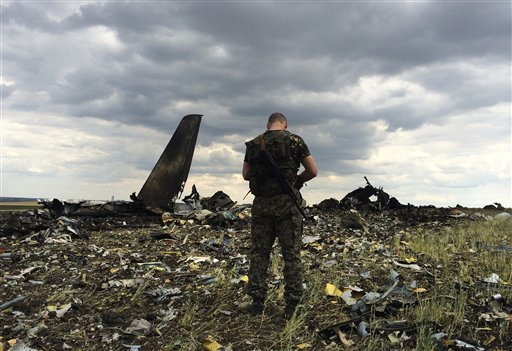 A pro-Russian fighter guards the site of remnants of a downed Ukrainian army aircraft Il-76 at the airport near Luhansk, Ukraine, Saturday, June 14, 2014. Pro-Russian separatists shot down the military transport plane Saturday in the country’s restive east, killing all 49 service personnel on board, Ukrainian officials said.