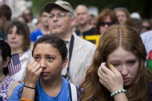 Michelle Zarisis, of Newtown, Conn., wipes away a tear at a rally outside city hall to call for tougher gun control laws, Saturday, June 14, 2014, in New York. The protest was underwritten by former New York Mayor Michael Bloomberg, one of the most visible gun control advocates in the U.S., and included relatives of some of those slain in the 2012 shooting rampage at Sandy Hook Elementary School. 
