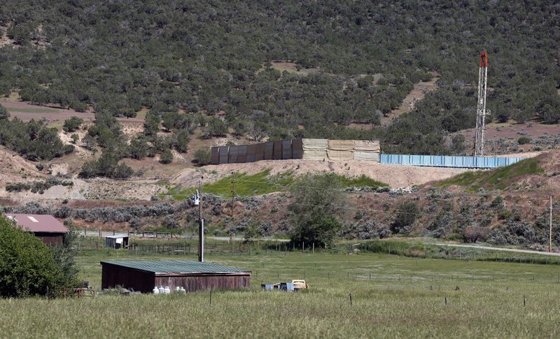 This photo taken June 9, 2014 shows  an oil and gas rig on a well pad is visible at right, adjacent to a ranch in New Castle, a small farming and ranching settlement on the Western Slope of the Rockies, in Colo. Four in 10 new oil and gas wells near national forests and fragile watersheds or otherwise identified as higher pollution risks escape federal inspection, unchecked by an agency struggling to keep pace with America's drilling boom, according to an Associated Press review that shows wide state-by-state disparities in safety checks.