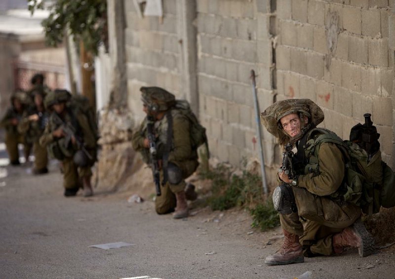 Israeli soldiers take positions during a military operation searching for three missing teenagers near the West Bank city of Hebron on Sunday.