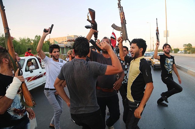 Shiite tribal fighters raise their weapons and shout against the al-Qaida-inspired Islamic State of Iraq and the Levant in Basra, Iraq, on Sunday.