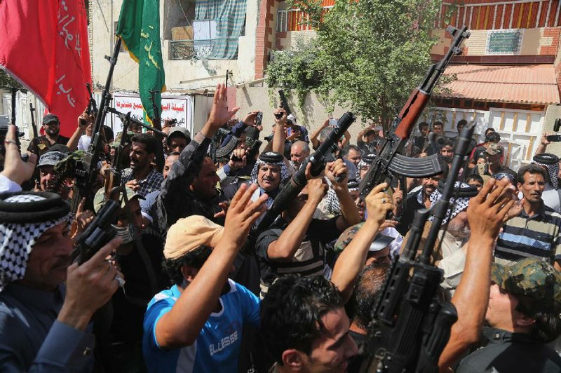 Shiite tribal fighters hoist their weapons and chant slogans Saturday in Baghdad as they mobilize to battle Islamic militant forces who have captured large swaths of territory north of the Iraqi capital.