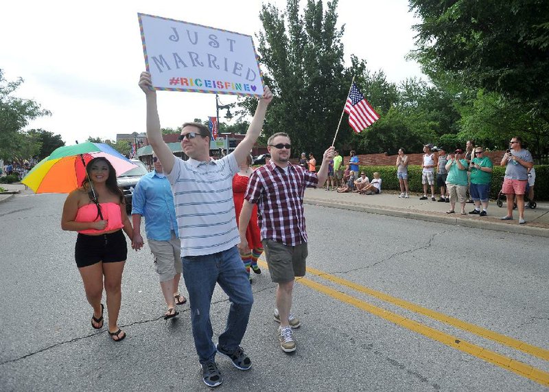 Todd Walters (front) walks Saturday with his domestic partner Mike Emery along Dickson Street as gay-rights supporters participate in the annual NWA Pride parade in Fayetteville.
