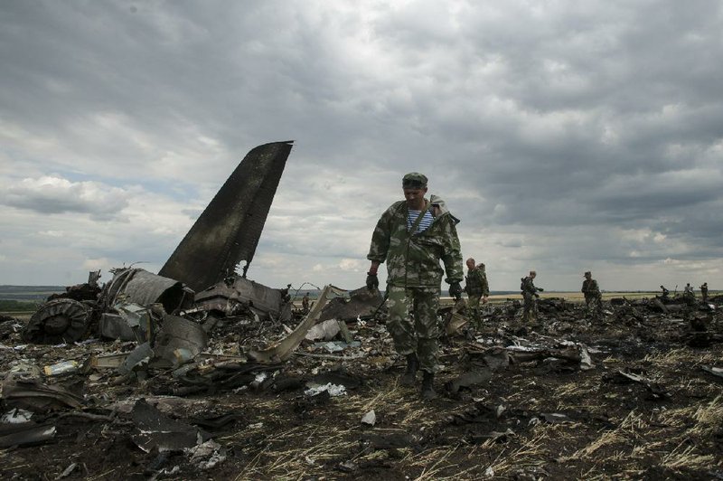 Pro-Russia fighters walk through the remnants of a Ukrainian military transport plane that was shot down Saturday as it approached the airport at Luhansk in eastern Ukraine.