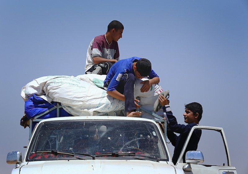 Iraqis who have fled the violence in their hometown of Mosul unload their car at Khazir refugee camp outside of Irbil, 217 miles north of Baghdad, Iraq, on Monday, June 16, 2014. 