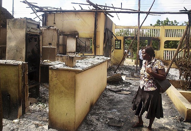 A woman observes the remains of the Breeze View Hotel, where residents watching the World Cup soccer tournament were attacked and killed by militants Monday in Mpeketoni, Kenya.