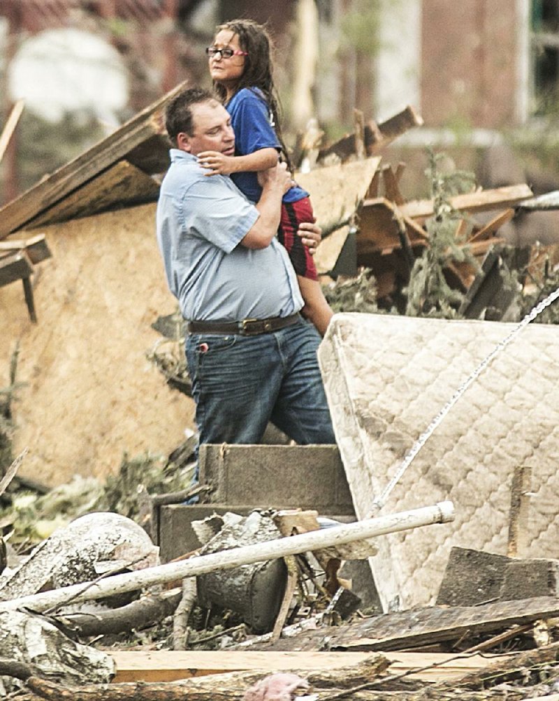 A man carries a girl after she was pulled from the basement of her destroyed home in Pilger, Neb., on Monday. A hospital spokesman said at least one person is dead and at least 16 more are in critical condition after two tornadoes swept through northeast Nebraska.