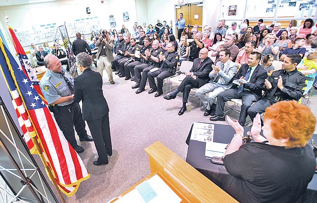 STAFF PHOTO ANTHONY REYES Ron Findley, left, accepts the Helen Bowman Civilian Employee of the Year award Monday from Kathy O&#8217;Kelley, Springdale police chief, during the 2014 Springdale Police Departments awards and promotion ceremony at the Springdale City Council chambers. Several Springdale police officers and civilian employees received awards for their work during the year.