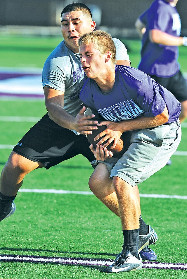 STAFF PHOTO ANDY SHUPE Myles Koch, right, Fayetteville sophomore, makes a catch Monday in front of junior Jonathan Betancourt during a 7-on-7 tournament for the Bulldogs&#8217; offensive line corps at Harmon Stadium in Fayetteville.