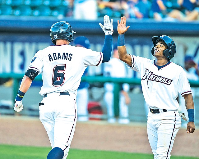 STAFF PHOTO ANTHONY REYES Lane Adams, left, high fives Justin Trapp, both with the Naturals, after Adams hit a two-run home run Monday against the Travelers at Arvest Ballpark in Springdale.