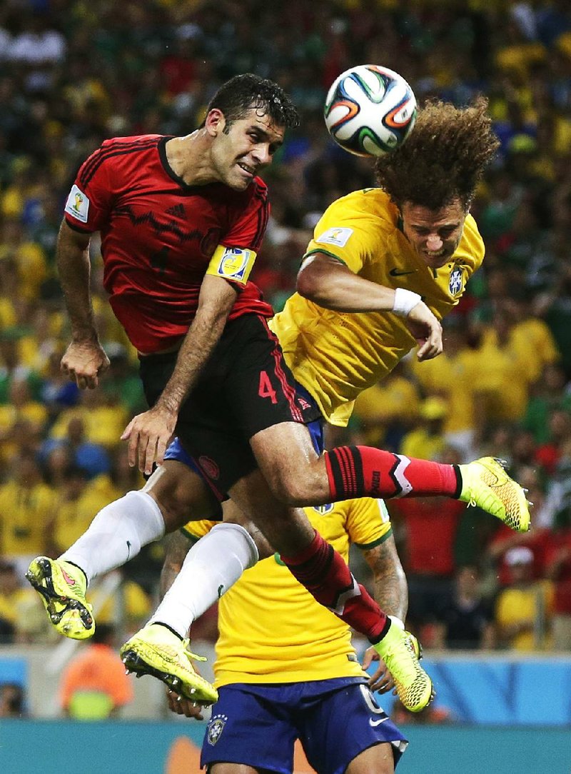 Mexico’s Rafael Marquez (left) and Brazil’s David Luiz head the ball together during Tuesday’s World Cup match at Fortaleza, Brazil.