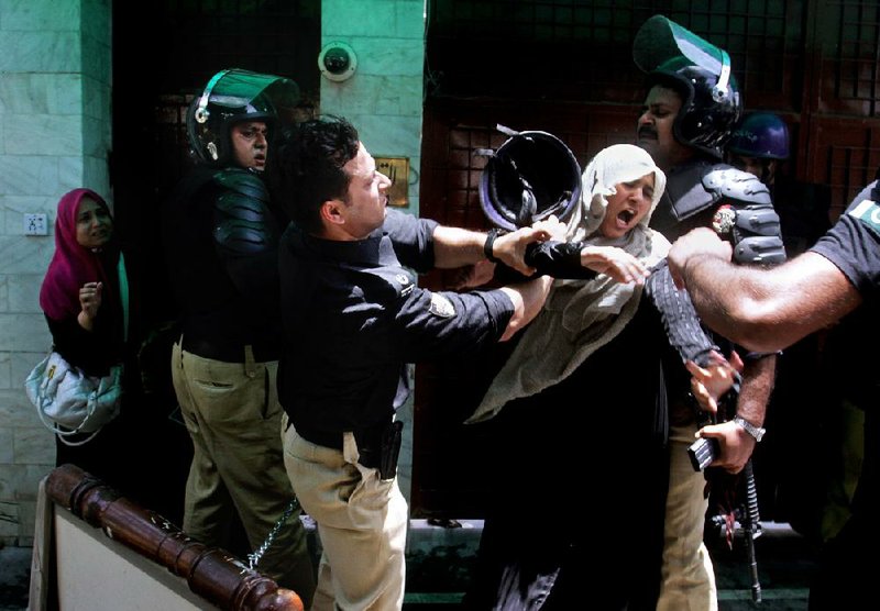 A Pakistani police officer scuffles with a female protester Tuesday in Lahore, where clashes between police and followers of a preacher have turned deadly.