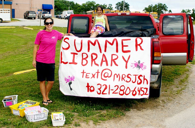 Staff Photo by Randy Moll Decatur math and science teacher Jacque Smith wants to keep Decatur young people reading over the summer months and operates a small mobile library service there on Fridays. She was assisted recently by her daughters.