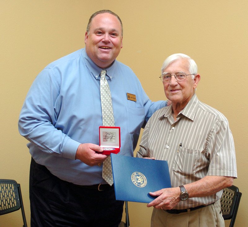 Evans honored at retirement Jeff Thacker, representing U.S. Congressman Steve Womack, presented Dodie Evans (right) with a medallion and a congressional proclamation honoring Evans for 61 years in the newspaper industry and for his service to Gravette and the surrounding communities. The presentation took place at an open house on Thursday in Gravette to honor Evans on the occasion of his retirement as editor emeritus from the Westside Eagle Observer. Evans owned and operated the Gravette News Herald for much of his newspaper career. Photo by Randy Moll