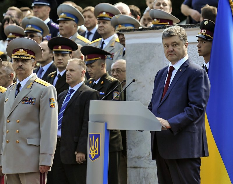 Ukrainian President Petro Poroshenko, right, attends a graduation ceremony at the Ukrainian military academy in Kiev, Ukraine, Wednesday, June 18, 2014. The Ukrainian president on Wednesday announced a plan to end the fighting in eastern Ukraine, promising a unilateral cease-fire after discussions with the Russian and German leaders, a potential major development to bring peace to the country. At left is acting Ukrainian Defense Minister Mykhailo Koval. 