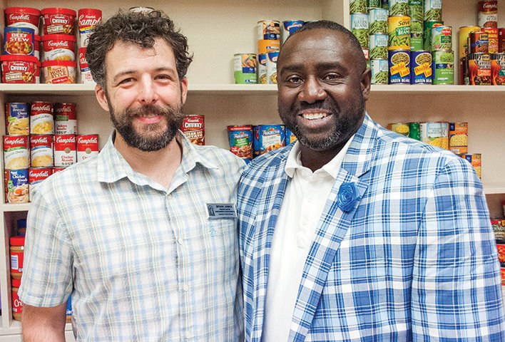 Brian James, left, and Marvin Williams stand by shelves in the Bear Essentials Food Pantry in Old Main at the University of Central Arkansas in Conway.