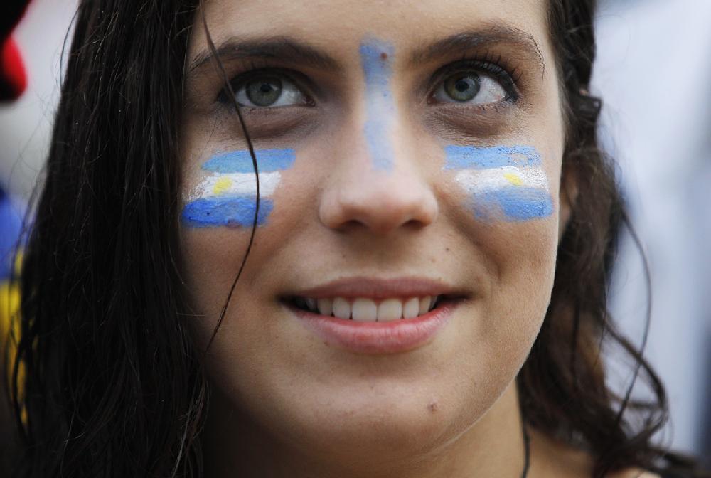 A Soccer fan with her face painted with Uruguay's team colors, watches a live telecast of the group D World Cup match between Uruguay and England, inside the FIFA Fan Fest area on Copacabana beach, in Rio de Janeiro, Brazil, Thursday, June 19, 2014. Luis Suarez scored twice to give Uruguay a 2-1 victory over England at the World Cup, making an instant impact on his return from injury to revive his team's Group D campaign. (AP Photo/Leo Correa)