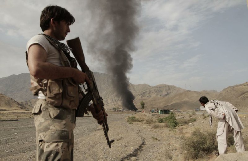 An Afghan policeman stands guard near the scene of an attack in Torkham, Nangarhar province, Afghanistan, Thursday, June 19, 2014. Afghan officials say three Taliban suicide bombers targeted NATO fuel trucks at the border with Pakistan, setting off a gunbattle with police guards. (AP Photo/Rahmat Gul)