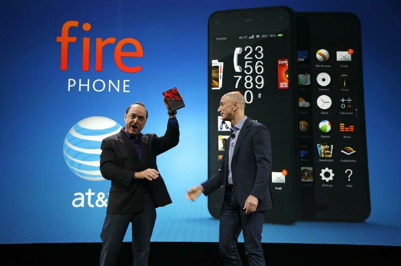 Ralph de la Vega (left), president and chief executive officer of AT&T Mobility, accepts a new Amazon Fire phone from Amazon CEO Jeff Bezos at a news conference Wednesday in Seattle.