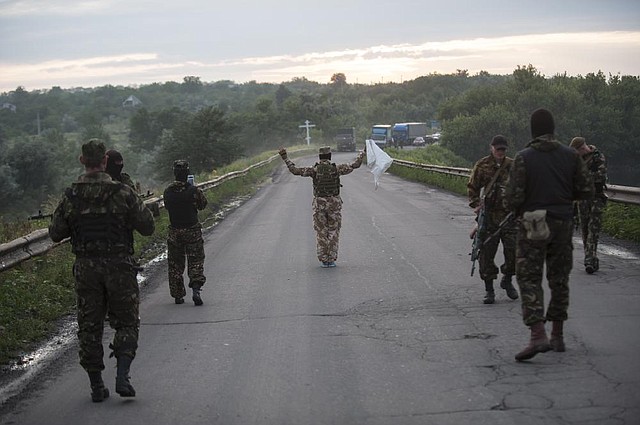 A pro-Russia fighter approaches government forces in the eastern town of Karlivka during a brief truce in which the rebels turned over the bodies of 49 Ukrainian troops killed when a plane was shot down last week near Luhansk.