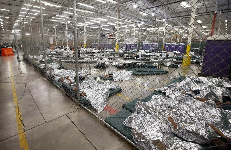 Detainees sleep or watch television Wednesday in a U.S. customs holding cell in Nogales, Ariz., where hundreds of children, mostly from Central America, are being held and processed.