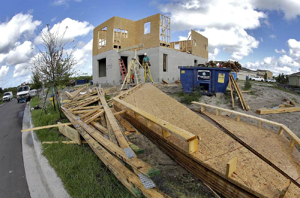 Builders work on a house in Riverview, Fla., in May. The Conference Board said Thursday that its index of leading indicators increased 0.5 percent last month but was held back by a drop in applications for building permits.