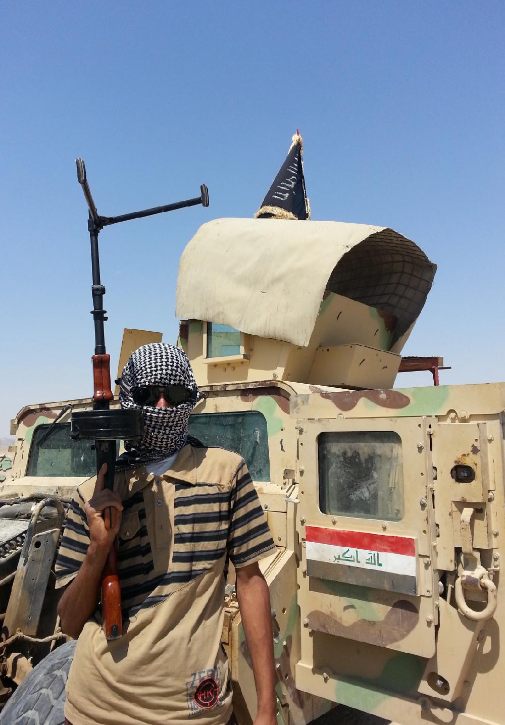 A militant stands with a captured Iraqi army Humvee at a checkpoint Thursday outside the Beiji refinery, about 155 miles north of Baghdad. The fighting at Beiji comes as Iraq has asked the U.S. for airstrikes targeting the militants from the Islamic State of Iraq and the Levant.
