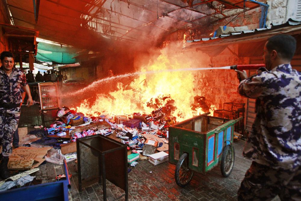 Members of the Palestinian Civil Defense hose down a shop that caught on fire due to clashes between Palestinians and Israeli soldiers in the West Bank city of Jenin, Thursday, June 19, 2014. Israeli soldiers clashed with Palestinians during an arrest raid early Thursday in the most violent confrontation so far in the weeklong search for three missing Israeli teens believed to have been abducted in the West Bank. Since the operation to locate the teens began a week ago, about 280 Palestinians have been arrested, the military said, including 200 members of Hamas. (AP Photo/Mohammed Ballas)