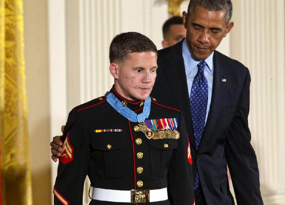 President Barack Obama reaches out to retired Marine Cpl. William "Kyle" Carpenter, after awarding him the Medal of Honor for conspicuous gallantry, Thursday, June 19, 2014, during a ceremony in the East Room of the White House in Washington. Carpenter received the Medal of Honor for his courageous actions while serving as an Automatic Rifleman in Helmand Province, Afghanistan. (AP Photo/Jacquelyn Martin)
