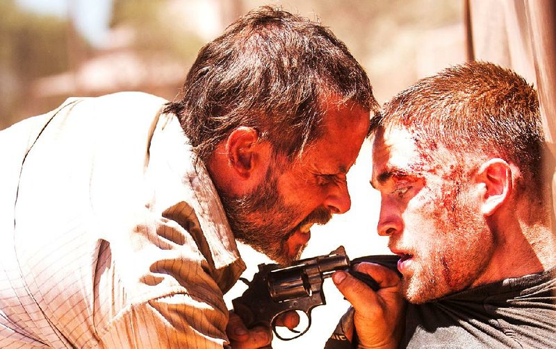 Eric (Guy Pearce) convinces a gut-shot Rey (Robert Pattinson) to help him in his quest to retrieve his stolen car in the dystopian thriller The Rover.