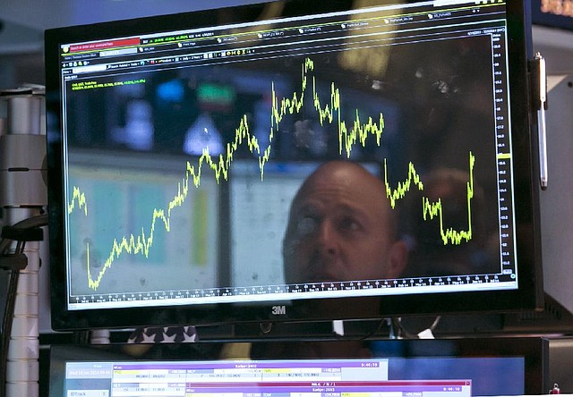 Specialist Jay Woods watches the video screen Wednesday at his post on the •oor of the New York Stock Exchange. The Standard and Poor’s 500 index closed at another record high.