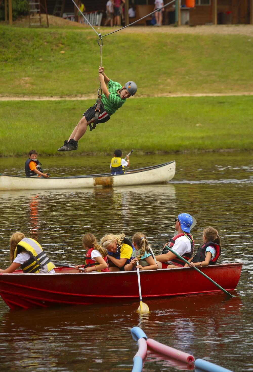 6/19/14
Arkansas Democrat-Gazette/STEPHEN B. THORNTON
Robbie Benning, 11, of Sheridan, flies on a zip line above other canoeing campers  at the Family Farm Christian Day Camp Thursday near Glen Rose. The camp host around 250 kids per week-long session for activities such as horseback riding, fishing, petting zoo, mixed in with devotional time.