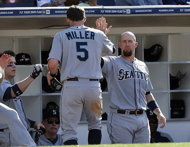 Seattle Mariners' Brad Miller is greeted by John Buck, right, and other teammates after scoring on a single by Robinson Cano in the fifth inning of a baseball game against the San Diego Padres Thursday, June 19, 2014, in San Diego. 