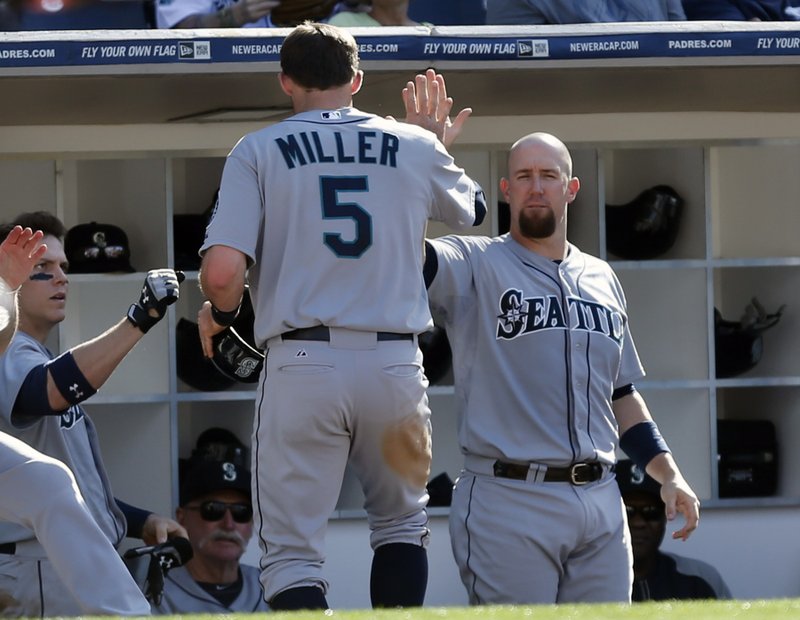 Seattle Mariners' Brad Miller is greeted by John Buck, right, and other teammates after scoring on a single by Robinson Cano in the fifth inning of a baseball game against the San Diego Padres Thursday, June 19, 2014, in San Diego. 