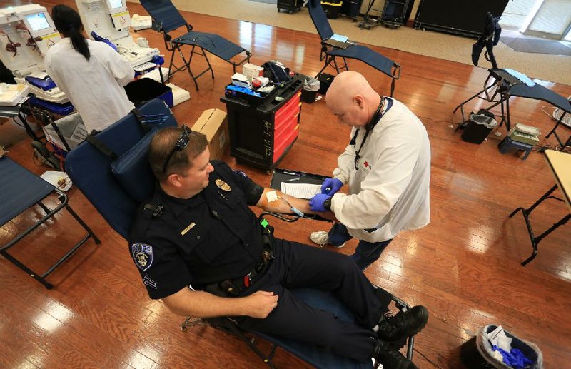Arkansas Democrat-Gazette/RICK MCFARLAND — North Little Rock Police Officer Todd Humphries has his blood drawn by Rich Armstrong, with the American Red Cross, at the Hays Senior Center on June 20. Humphries was participating in the Battle of the Badge which challenges police and firefighters to out-do each other in numbers giving blood.