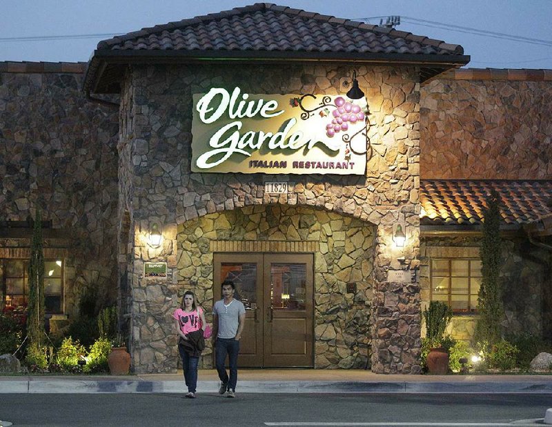 In this May 22, 2014 photo, patrons exit an Olive Garden Restaurant, a Darden restaurant brand, in Short Pump, Va. Darden's fiscal fourth-quarter profit dropped 35 percent, dragged down by charges and costs tied to its strategic plan to reshape the restaurant company. (AP Photo/Steve Helber)