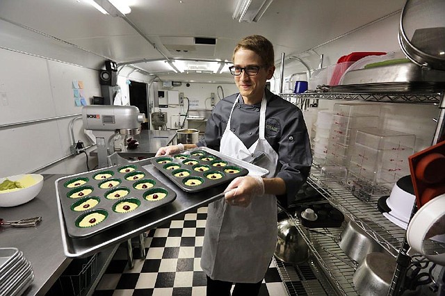 In this June 19, 2014 photo, chef Alex Tretter carries a tray of  cannabis-infused peanut butter and jelly cups to the oven for baking, at Sweet Grass Kitchen, a well-established gourmet marijuana edibles bakery which sells its confections to retail outlets, in Denver. Sweet Grass Kitchen, like other cannabis food producers in the state, is held to rigorous health inspection standards, and has received praise from inspectors, according to owner Julie Berliner. (AP Photo/Brennan Linsley)
