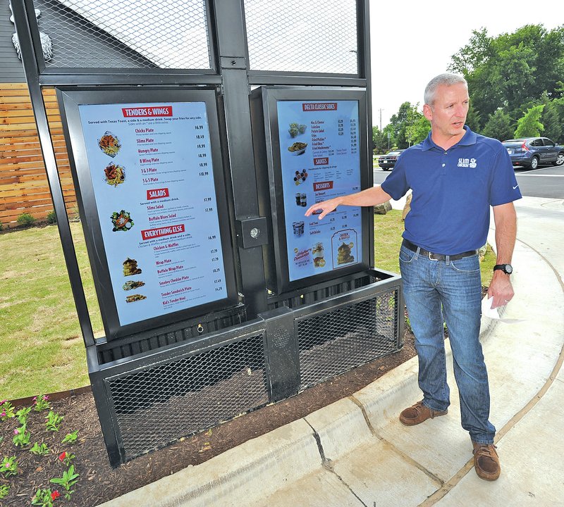 STAFF PHOTO ANDY SHUPE Greg Smart, a co-founder of Slim Chickens, talks about the new digital, cloud-based menu board system the company&#8217;s restaurants will be employing.