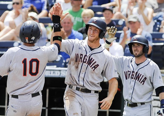 Virginia’s Joe McCarthy (center) and Branden Cogswell (right) are greeted by teammate Brandon Downes after scoring on a two-run single by Robbie Coman in the fourth inning of the Cavaliers’ 4-1 victory over Mississippi on Saturday at the College World Series in Omaha, Neb.
