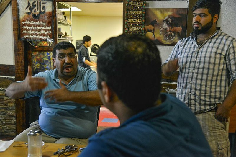Kareem Mohammed, left, talks with Waleed Khohor, center, about the situation in their home country of Iraq as Mohammed's son Abbas Hadi looks on at Sinbad Restaurant, owned by prominent local Iraqi refugee Kareem Mohammed on Tuesday, June  17, 2014, in Alexandria, Va.  The local Iraqi refugee community is concerned as it watches Iraq and its Shiite-led government start threatened by Sunni extremists. Illustrates IRAQ-EXILES (category a), by Pamela Constable (c) 2014, The Washington Post. Moved Saturday, June 21, 2014. (MUST CREDIT: Washington Post photo by Jahi Chikwendiu)
