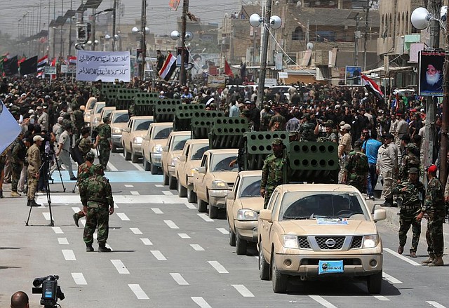A line of rocket-launcher-equipped trucks moves by as Shiite volunteers parade through the Sadr City area of Baghdad on Saturday to show their readiness to take on Sunni insurgents.