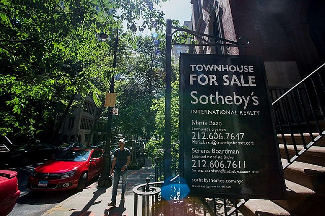 A pedestrian walks past a Sotheby's "For Sale" sign displayed outside of a townhouse in New York, U.S., on Monday, June 23, 2014. Americans snapped up previously owned homes in May in the biggest monthly sales gain in almost three years, a sign the residential real estate market is regaining its footing after a stumble early in the year. Photographer: Craig Warga/Bloomberg